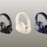 Três fones de ouvido Soundcore Q20i nas cores preto, bege e azul escuro, dispostos lado a lado contra um fundo gradiente neutro.