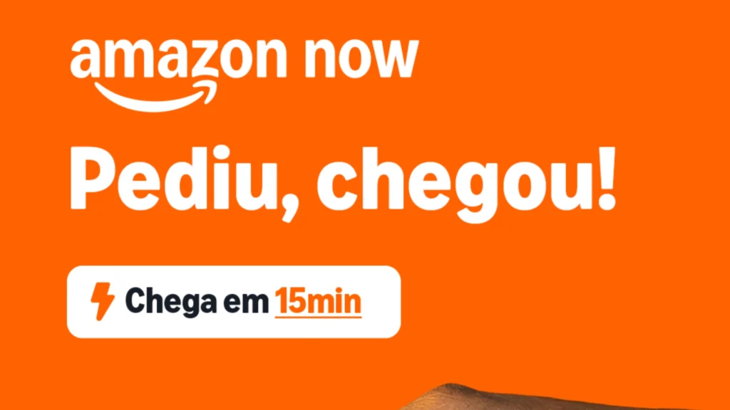 A imagem é um banner publicitário digital com fundo laranja vibrante. No canto superior esquerdo, encontra-se o logotipo oficial "amazon now" escrito em branco, acompanhado da clássica seta em formato de sorriso da marca. No centro da imagem, em destaque e com letras grandes e brancas, está a frase "Pediu, chegou!". Logo abaixo, há um botão branco retangular com bordas arredondadas que contém um ícone de raio na cor laranja ao lado do texto em preto e laranja: "Chega em 15min" (com o "15min" sublinhado). Na borda inferior direita, é possível ver o detalhe sutil de uma embalagem de papelão sendo segurada. A imagem ilustra a rapidez do novo serviço Amazon Now no Brasil.