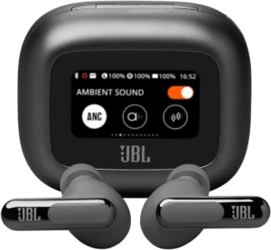 Uma visão frontal do estojo de carregamento preto fosco dos fones de ouvido JBL Live Beam 3. O estojo tem uma tela touchscreen colorida exibindo "AMBIENT SOUND", uma opção de alternância ligada e três ícones circulares (ANC, ícone de fala "a", ícone de ondas sonoras). O logotipo da JBL está abaixo da tela. À frente do estojo estão dois fones de ouvido intra-auriculares cinza escuro correspondentes, com pontas de silicone cinza e hastes cinza escura polida com o logotipo da JBL.