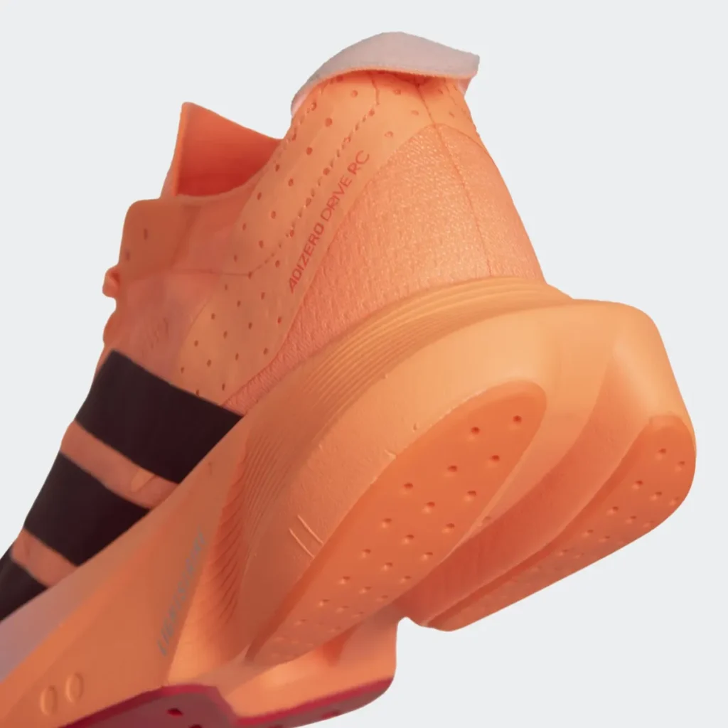 Visão aproximada do calcanhar do tênis Adidas Adizero Drive RC Feminino laranja pastel, mostrando detalhes do cabedal respirável e solado robusto.