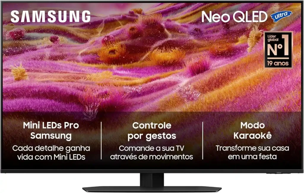 Smart TV Samsung QN90F Neo QLED, excelente opção entre as melhores TVs para a Copa do mundo 2026, exibindo uma imagem texturizada em tons vibrantes de rosa e roxo. Na tela, há chamadas para os recursos Mini LEDs Pro, controle por gestos e modo karaokê, além do selo de líder global em vendas.