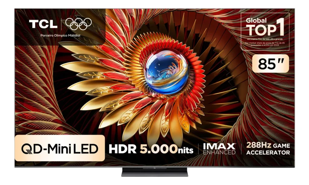 Smart TV TCL 85C8K QD-MiniLED, a opção de tela gigante entre as melhores TVs para a Copa do mundo 2026, vista de frente apoiada em sua base central. A tela exibe uma arte abstrata e vibrante com formas que lembram penas douradas e vermelhas em espiral ao redor de uma esfera azul brilhante. O display destaca características técnicas de peso: 'QD-Mini LED', 'HDR 5.000nits', 'IMAX ENHANCED' e '288Hz GAME ACCELERATOR'. Há também os selos indicando '85 polegadas' e a marcação de 'Global TOP 1 em marca TVs de tela ultra grande'.
